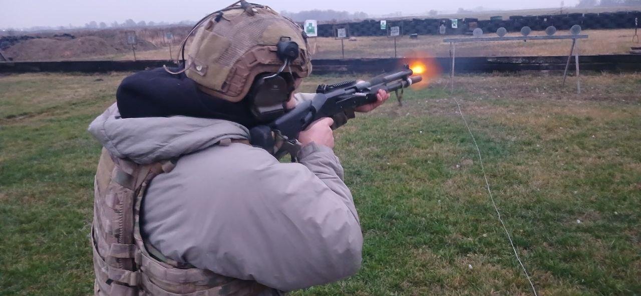 A Ukrainian soldier firing a semi-automatic shotgun downrange during a training exercise